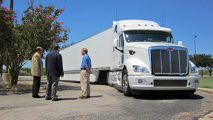 Peterbilt representatives Don Vollmar, Director of Product Planning (left) and Rick Mihelic, Manager of Vehicle Performance and Engineering Analysis (right), present the advanced concept SuperTruck vehicle for U.S. Rep. Michael C. Burgess, M.D., (center) during the Energy Summit & Fair in Denton, Texas. 